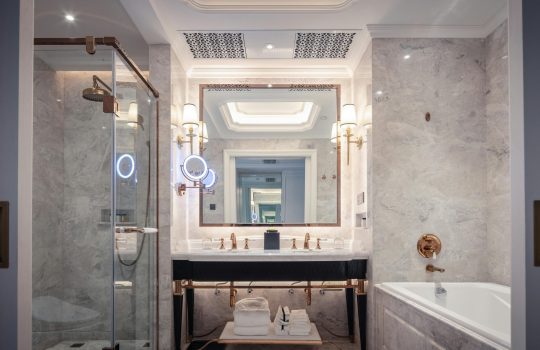 Elegant bathroom featuring a marble sink, bathtub, and mirror with ambient lighting.